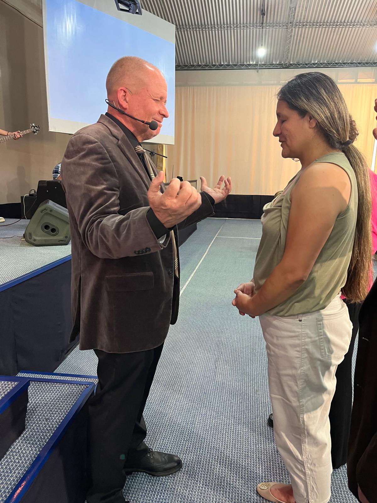 David Larson praying with a young woman after the service