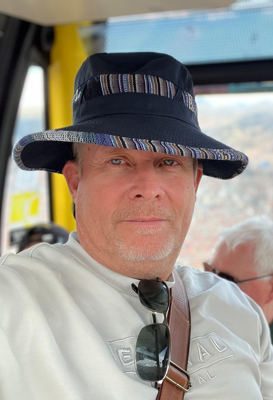 David Larson wearing a traditional Bolivian hat in a cable car above La Paz